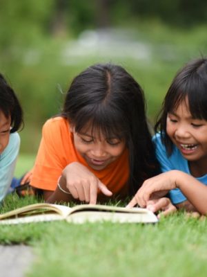 Group of children lying reading on grass field